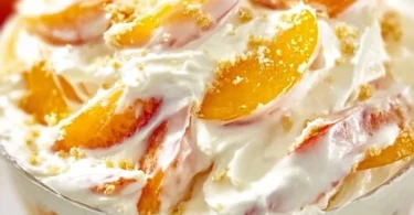 A delicious Peach Cheesecake Salad topped with fresh peaches and creamy cheesecake filling.