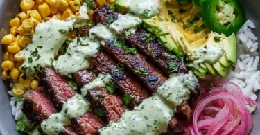 Steak bowl with avocado, roasted corn, and cilantro cream sauce on a plate